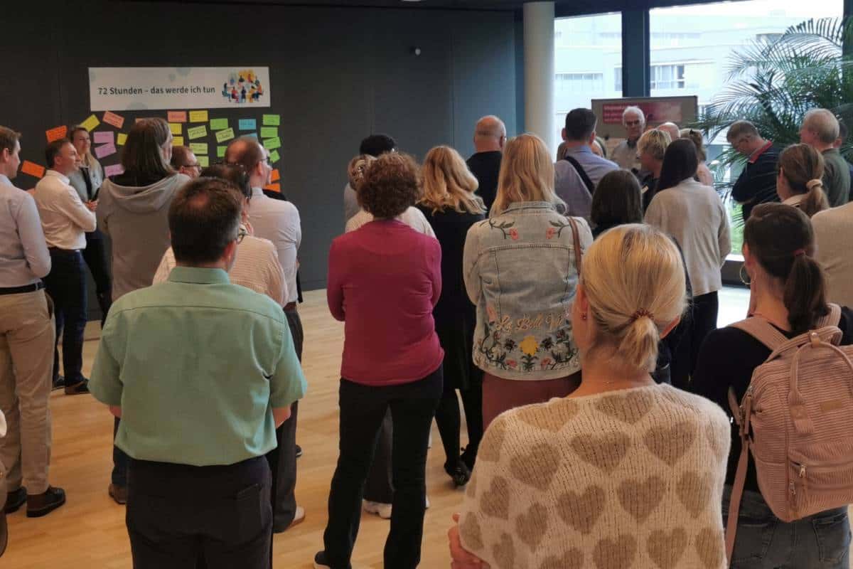Teilnehmende der DGUV Trainertage 2026 in Dresden stehen vor einer Pinnwand mit farbigen Moderationskarten zur Zukunftswerkstatt.