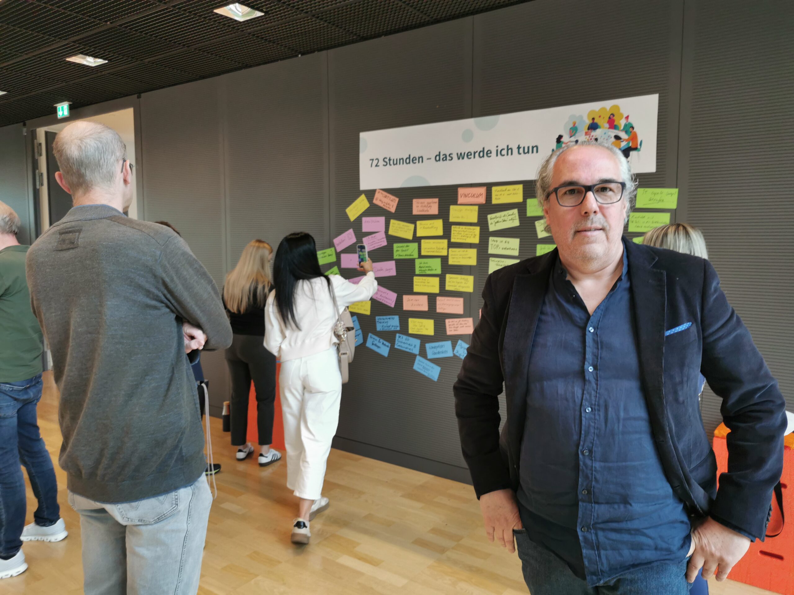 Victor Labra Holzapfel bei den DGUV Trainertagen 2026 in Dresden vor einer Pinnwand mit Ergebnissen der Zukunftswerkstatt.